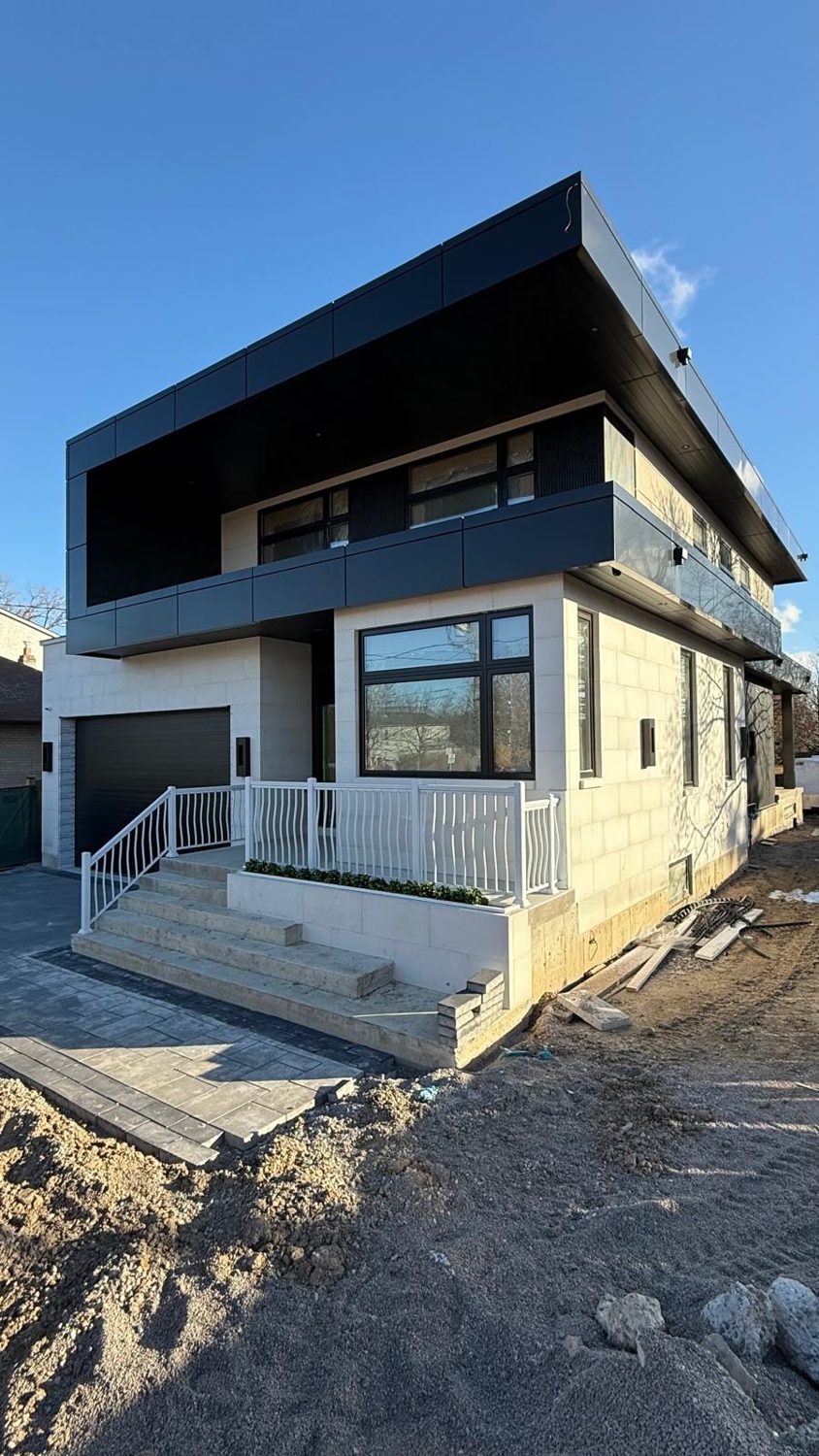 Front corner view of the Bainbridge custom home by Danclair Construction, modern white stone facade with black cantilever and covered porch