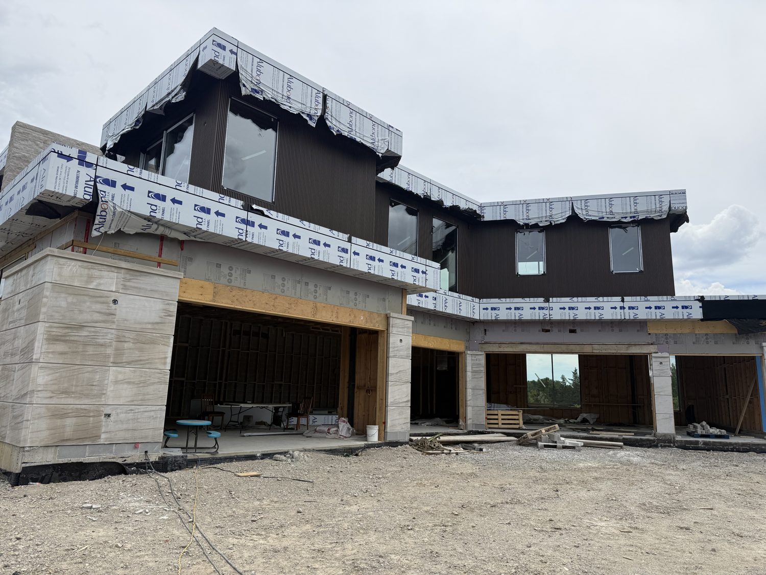 Front elevation of the Bellini custom home by Danclair Construction under construction, stone columns and dark cladding