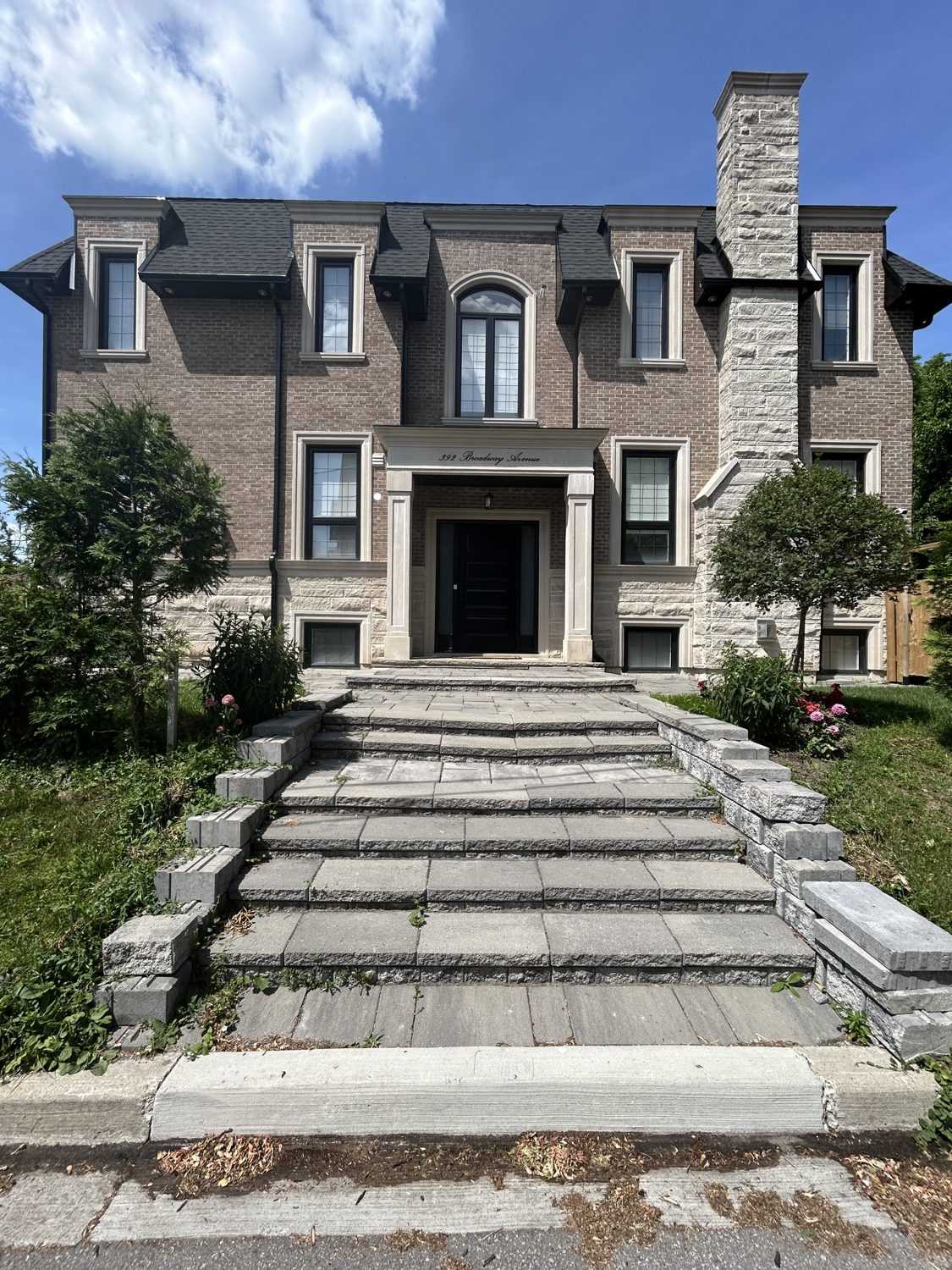 Front elevation of the Broadway custom home by Danclair Construction, brown brick and stone facade with arched feature window