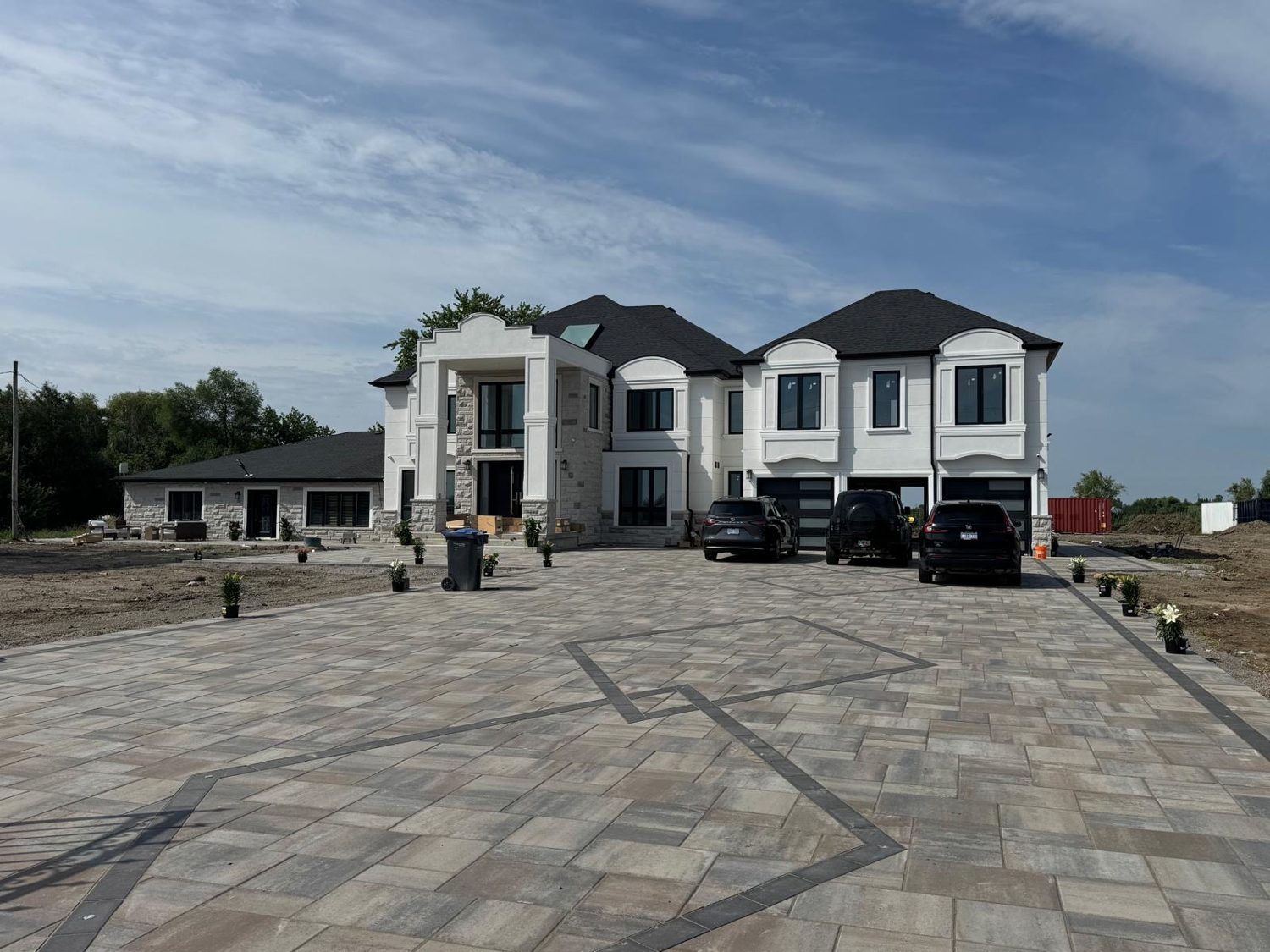 Front exterior of the Centreville Creek custom home by Danclair Construction, stucco and stone facade with interlock paver driveway