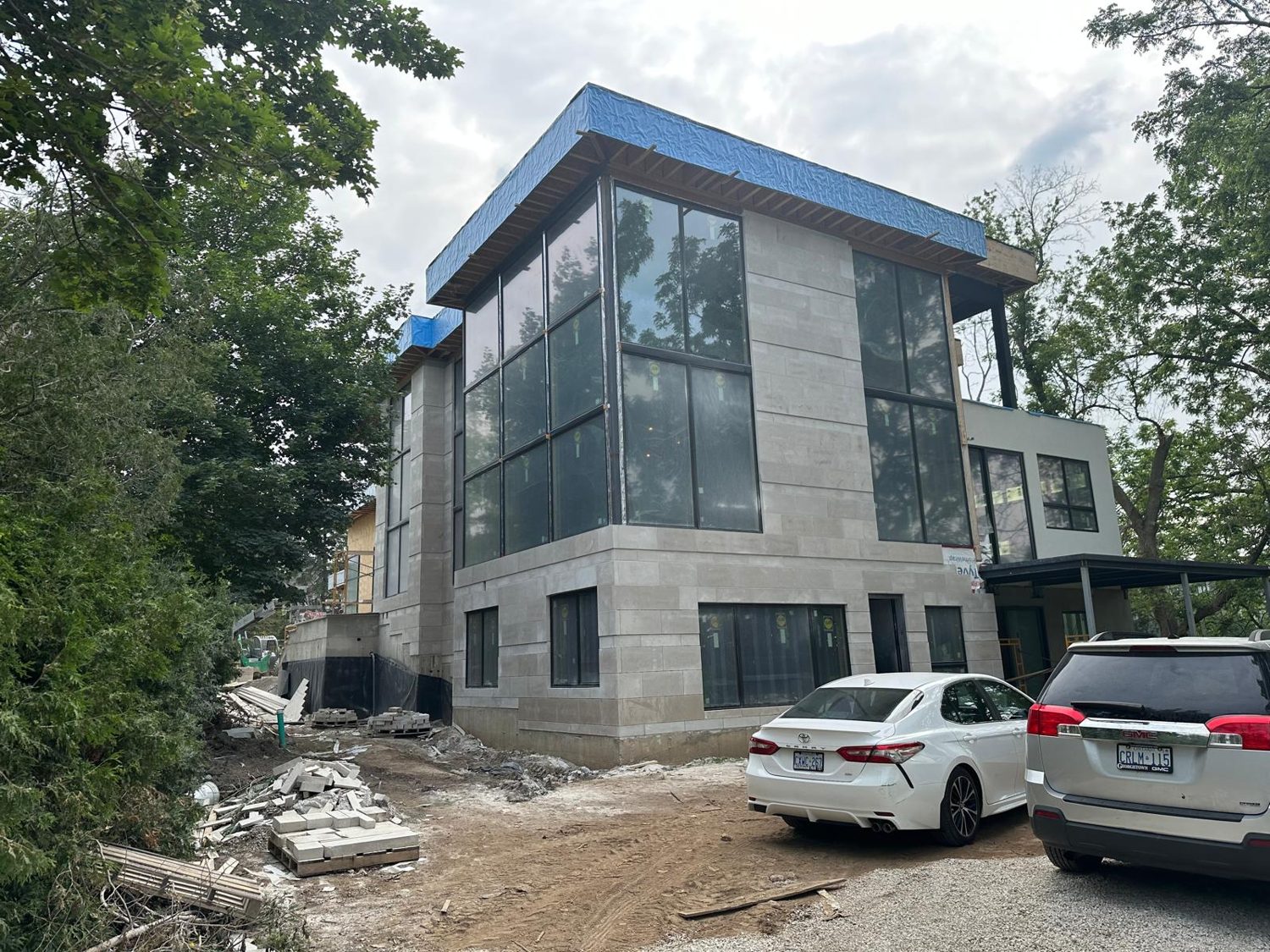 Exterior of the Churville custom home by Danclair Construction under construction, three storey stone facade with floor to ceiling windows