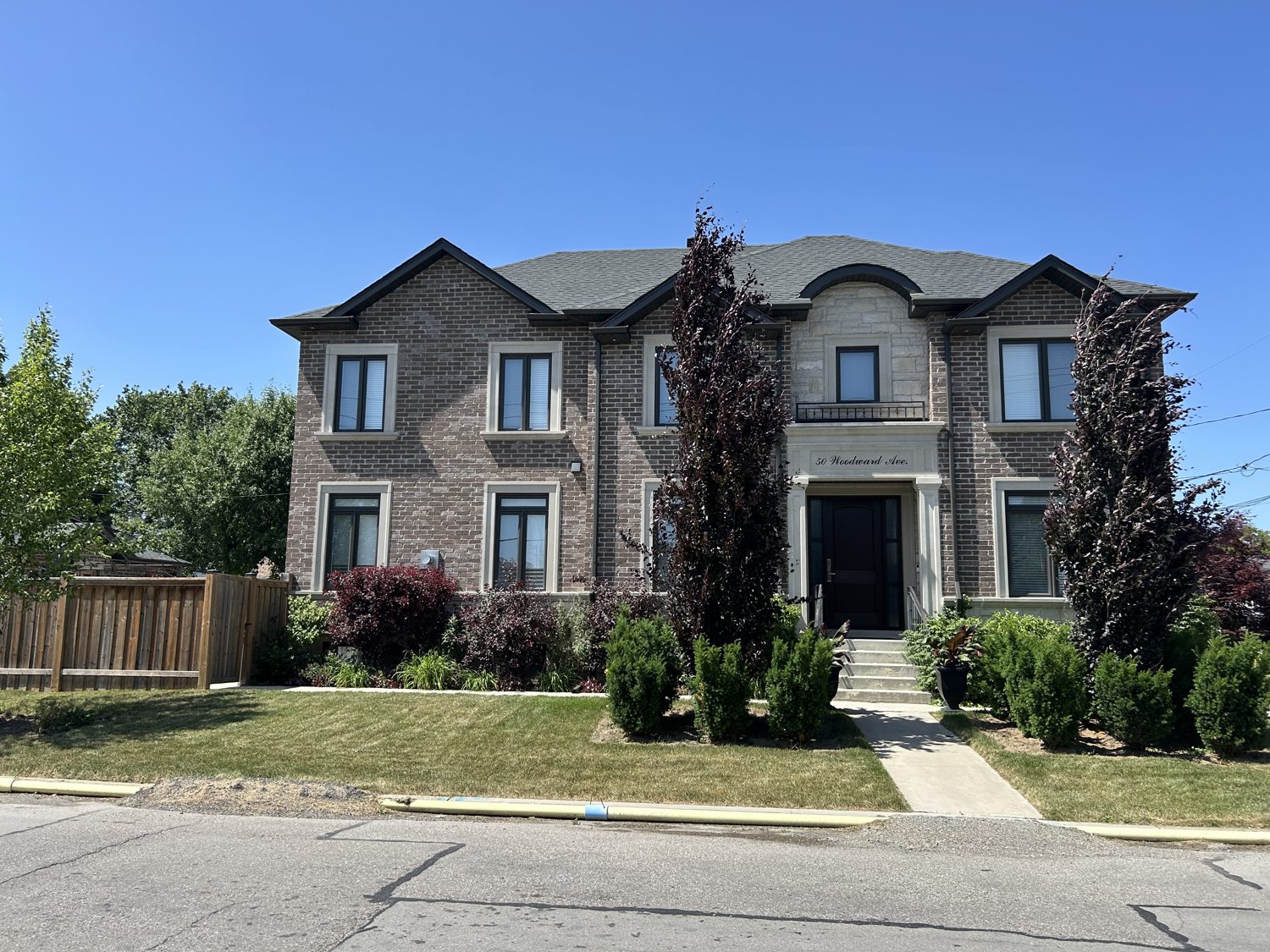 Front elevation of the Dalbeattie custom home by Danclair Construction, grey brick and stone facade with landscaped garden