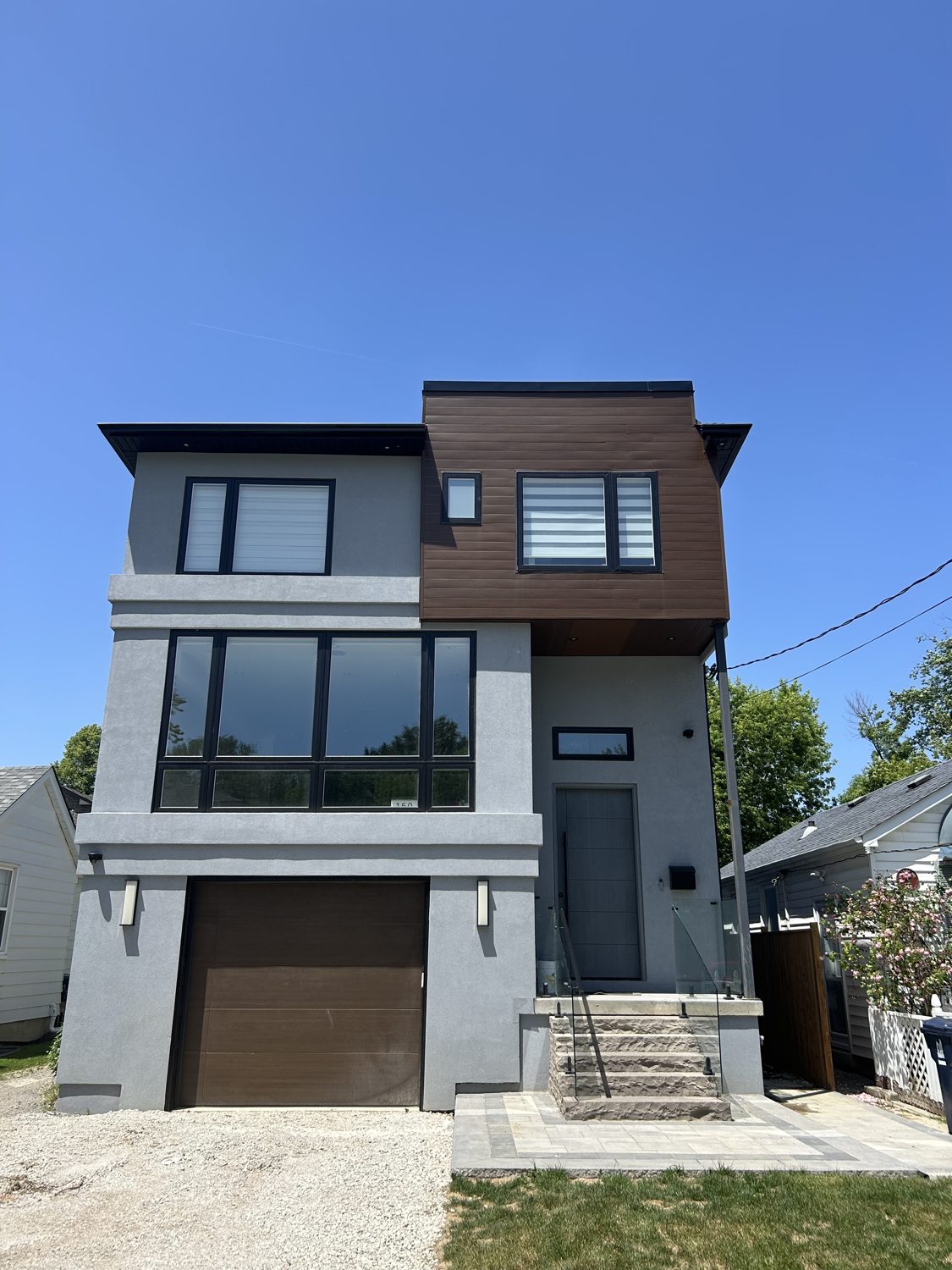 Front elevation of the Hillside custom home by Danclair Construction, modern grey stucco facade with wood accent cladding