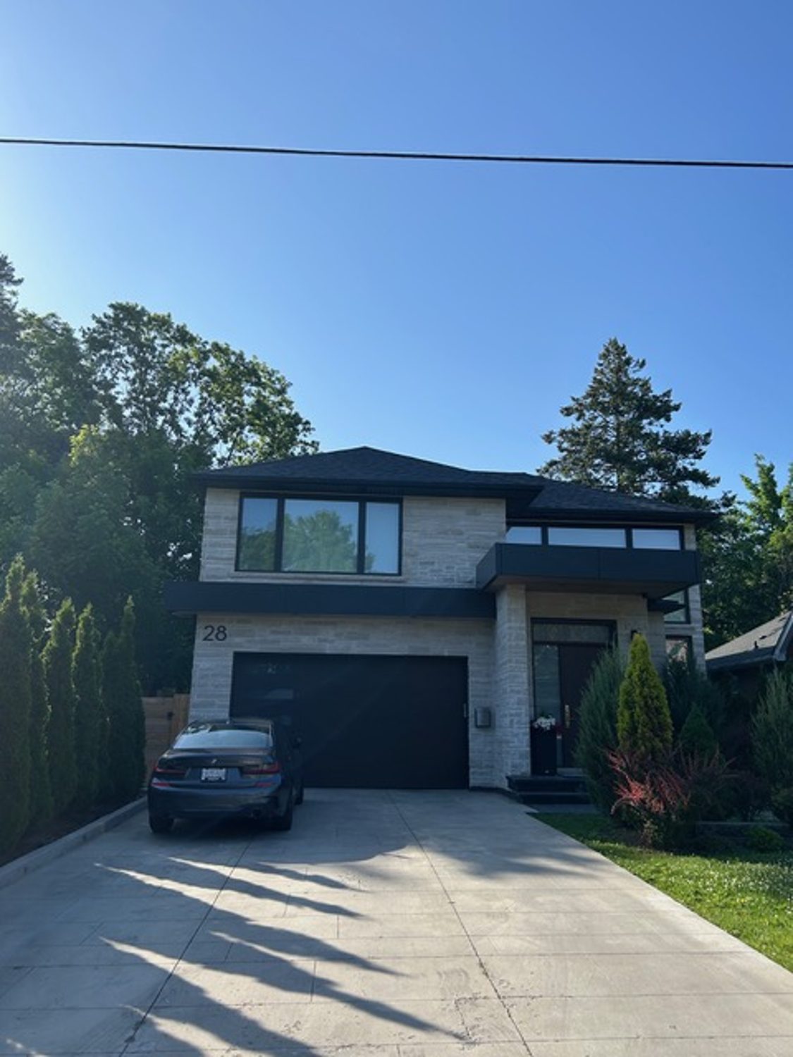Front elevation of the Inglewood custom home by Danclair Construction, modern stone and stucco facade with black accents and single garage