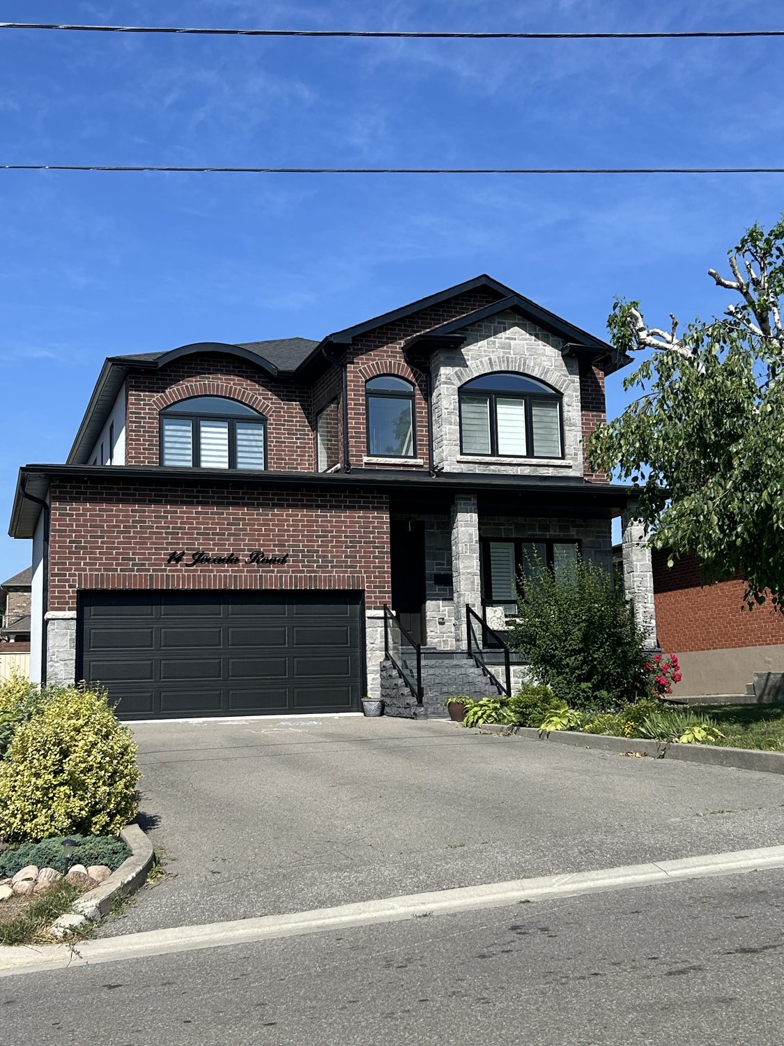 Front elevation of the Jocada custom home by Danclair Construction, red brick and stone facade with double garage