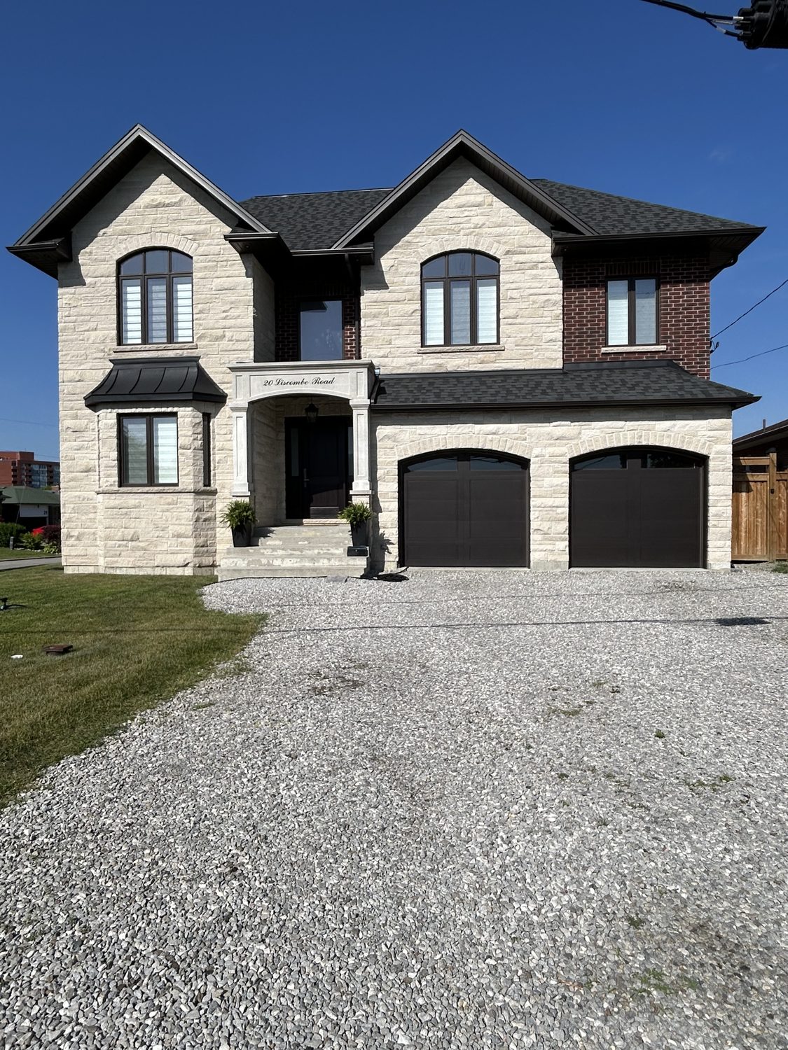 Front elevation of the Liscombe custom home by Danclair Construction, stone and brick facade with double garage