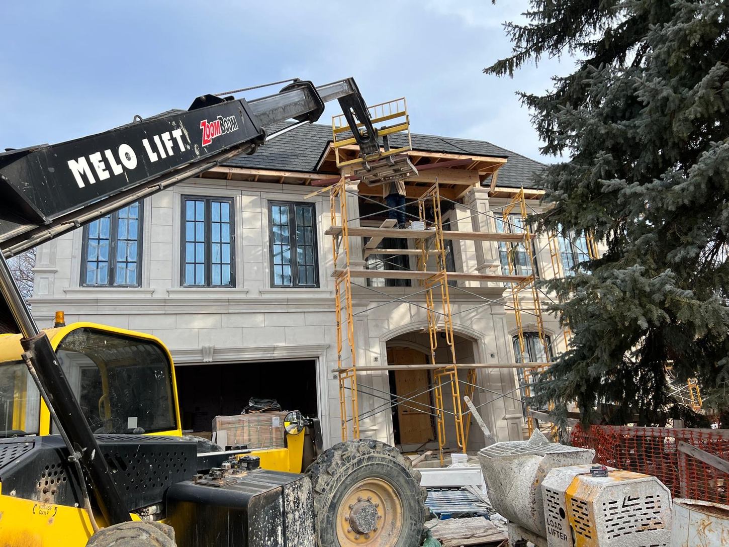 Front exterior of the North Park custom home by Danclair Construction during construction, stone facade with equipment on site