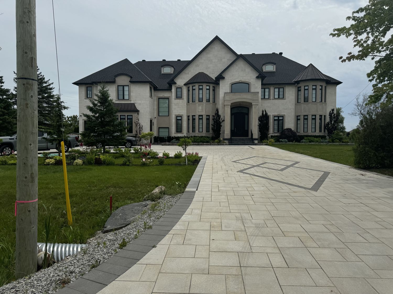 Front exterior of the Tortoise custom home by Danclair Construction, stone facade with interlock stone driveway