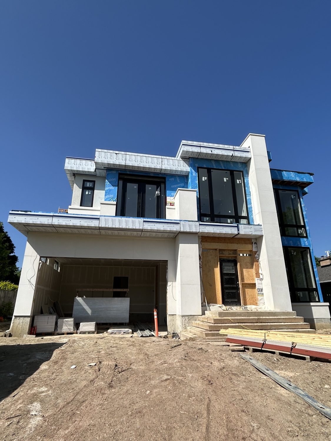 Front elevation of the Wareham custom home by Danclair Construction under construction, modern stucco facade with black windows